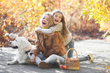 Two sisters on fall background. female on autumn skale. Girls having fun outdoors with their pet. People and dog.