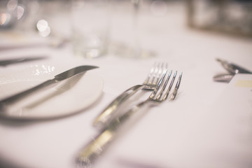 Cutlery, knives, fork and plates on a table in a restaurant before dinner close up
