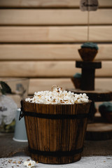 Details of a festival catering: fruits, cupcakes, popcorn and cake. Beautifully decorated table. Delicious candy bar at the wedding ceremony close up. Popcorn in wooden bucket