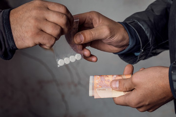 A person with money buys a dose of cocaine or heroin or other drug from a drug dealer