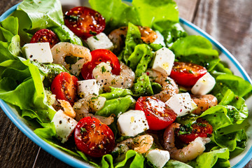 Salad with shrimps and feta cheese on wooden table