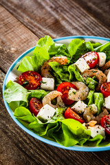 Salad with shrimps and feta cheese on wooden table