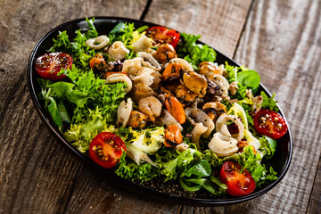 Salad with seafood and vegetables on wooden table