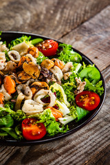 Salad with seafood and vegetables on wooden table