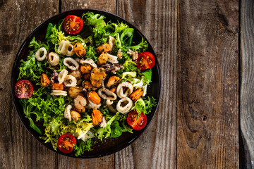 Salad with seafood and vegetables on wooden table