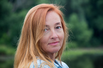 Portrait of adult woman against a green blurred background of plant origin.