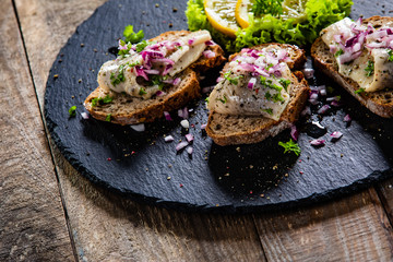 Marinated herring fillets on slices of bread on black stone