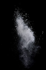 Obraz premium White powder splash isolated on black background. Flour sifting on a black background. Explosive powder white