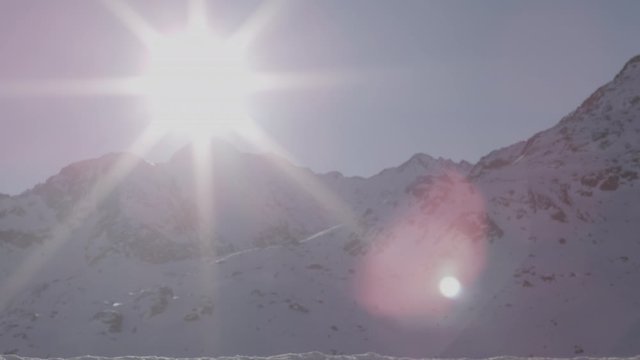sun lens flare above alpine mountain peak serfaus