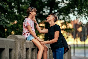 Mother talking with daughter sitting at the fence