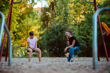 Mother and daughter sitting on a swing and having serious conversation
