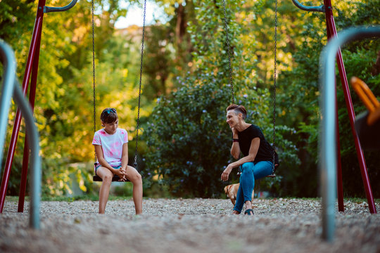 Mother And Daughter Sitting On A Swing And Having Serious Conversation