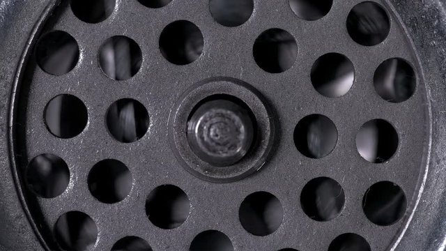 A meat grinder close-up, you can see the rotation of the knife with four blades and the grill with holes through which the meat passes 4K