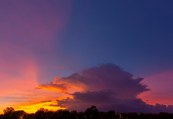 Panorama of thunderstorm clouds lit up in the colors of sunset.