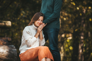 Couple in love outdoor standing in a beautiful colorful forest. Man's hand on he girlfriend's face.