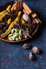 Dry warming Indian spicesin on plate for autumn winter meal on dark blue concrete background.