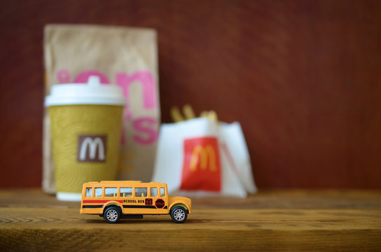 Small school bus and McDonald's junk food on wooden table