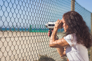 Movie maker working with 8 mm film camera through a wire fence