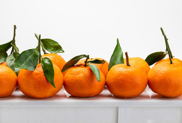 Fresh and raw tangerines with green leaves on a white table. Isolated on white background.