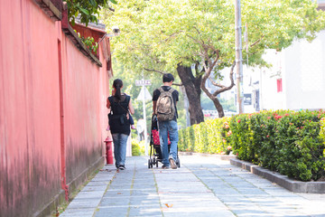 Fototapeta na wymiar Nuclear family /couple with baby walking beside Taiwan historic site / Confucius Temple in Tainan, Taiwan.