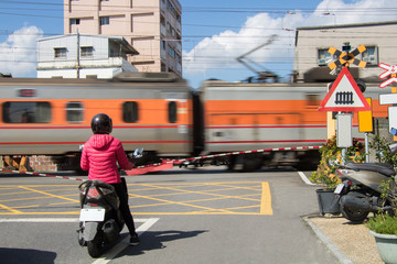 Motorcyclists wait patiently for a train to pass at a railway level crossing in Yilan, Taiwan.