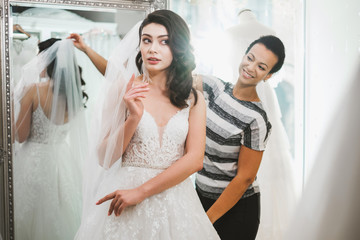 Naklejka premium Beautifu bride choosing wedding dress in a wedding salon