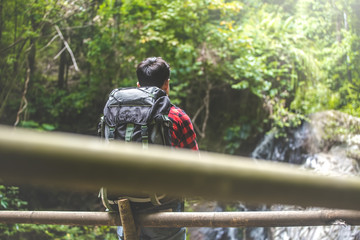 Naklejka premium Hiker man with backpack in front of waterfall. travel concept