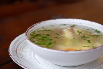 chicken soup in white plate on wooden background