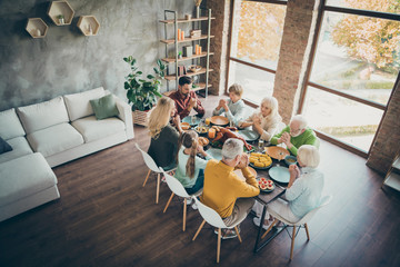 Top above high angler photo of serious dreamy large family meeting retired people preteen kids meeting sit table have thanksgiving celebration enjoy meal roasted chicken poultry pray in house