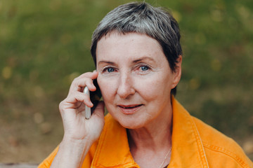 Portrait of a beautiful senior woman. Happy senior woman on the city streets using cellphone.