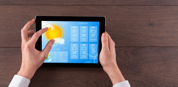 Man hand checking weekly weather forecast on tablet