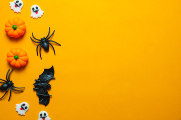 Halloween holiday concept, Spooky pumpkins, black spider, bats and tiny ghost in orange background with copy space for text, Top flat view wallpaper