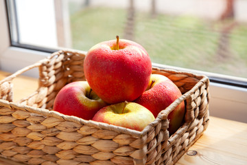 bunch of apples in a wicker basket by the window