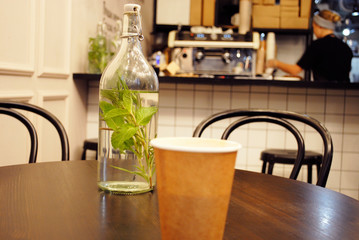 paper Cup and glass bottle on the table in the cafe