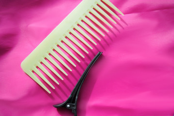 green comb and hair clothespin on pink background