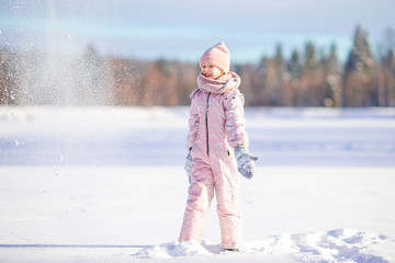 Portrait of little adorable girl in snow sunny winter day