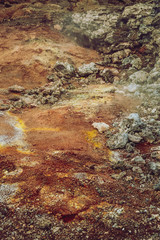 Closeup of Leirhnjukur old black lava field with red and orange soil and smoke coming from ground in Iceland, overcast day in summer , film effect with grain