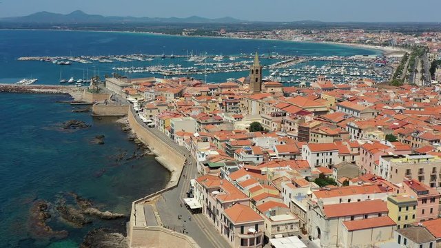 Aerial shot over Alghero old town, cityscape view on a beautiful day with harbor and open sea in view. Alghero, Italy. Panoramic aerial view of Alghero, Sardinia, Italy.