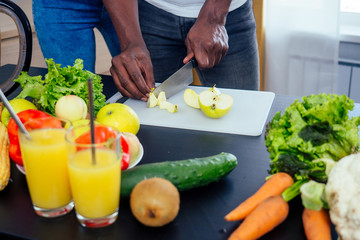 close up photo of afro male hamds cutting apple,eggplant and kivi