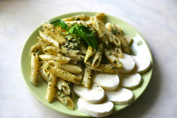 Pasta penne with pesto fresh homemade sauce and cherry and basil. 