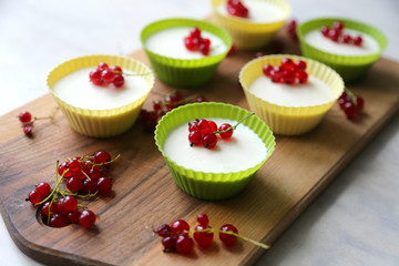 Italian dessert panna cotta with fresh red currants served in silicon molds form on wooden tray and...