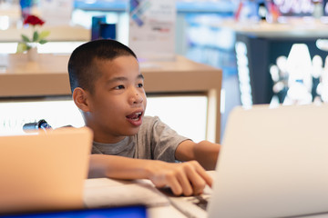 Disabled child on wheelchair trying to use a computer with excitement in an IT shop , Special children's lifestyle, Life in the education age of special need kids, Happy disability kid concept.