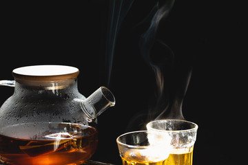The steam from a cup or pot of coffee or tea on the old wood table and black background, Warm drinks make good healthy, Selective focus.