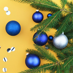 Christmas tree branch decorated with blue toys on an orange background.