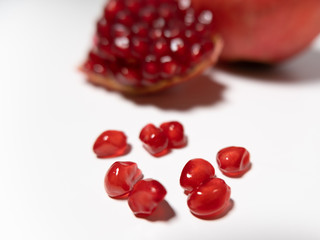 Pomegranate seeds spilling onto white table. Close up. Shallow depth of field.