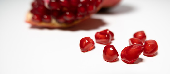 Pomegranate seeds spilling onto white table. Close up. Shallow depth of field.