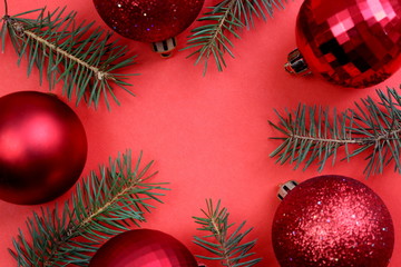 red flickering Christmas toy lies on a red background with sprigs of spruce
