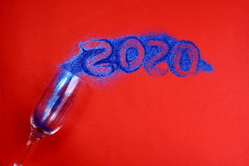 from the overturned glass splattered splashes of shiny confetti with the number 2020