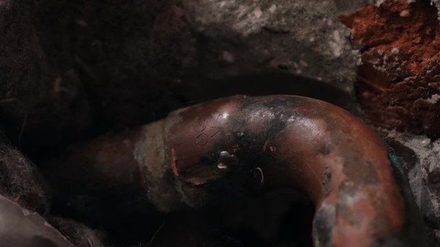 Damaged water pipe in the bathroom wall; missing isolation on the copper pipe; close up shot