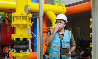 Engineer with his walkie-talkie, radio reciever to communicate and routine check process in factory.